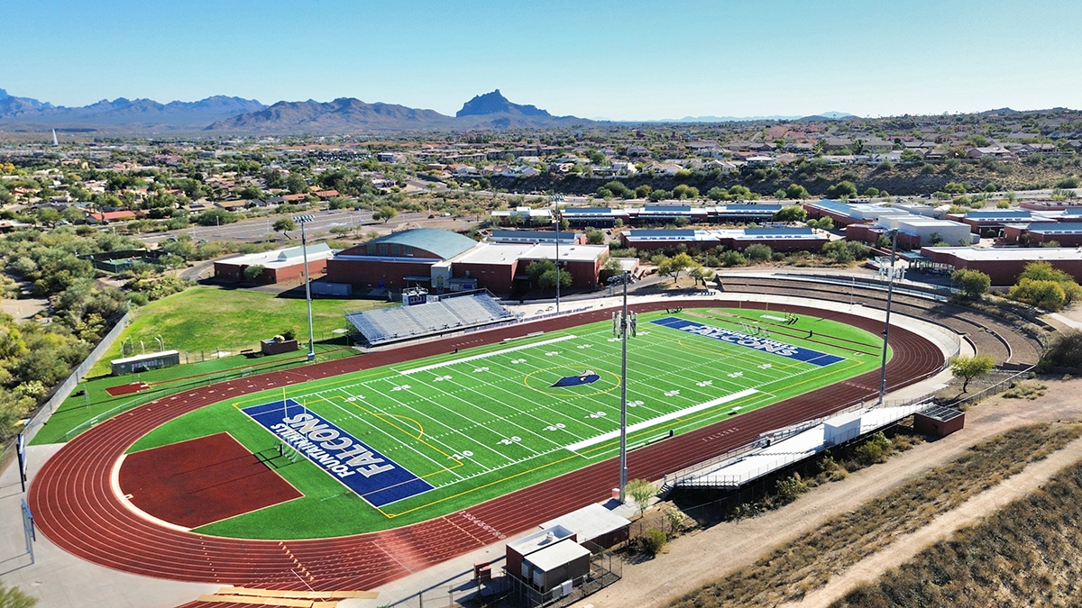Aerial shot of Fountain Hills High School football field with green turf, bleachers, and surrounding landscape.